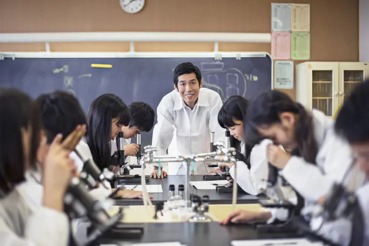 Science teacher with students using microscopes.
